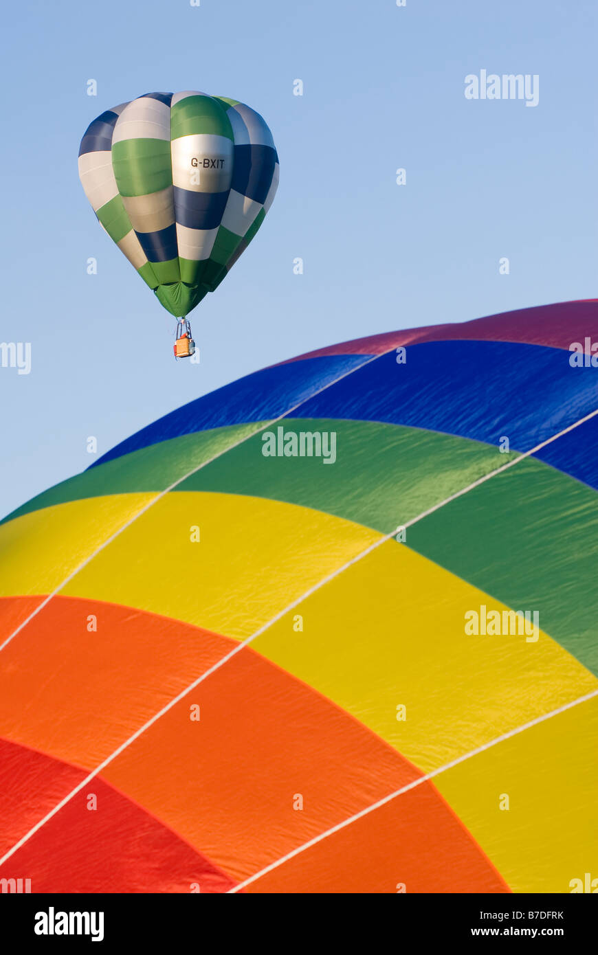 Hot air balloon taking off with another hot air balloon inflating in the foreground Stock Photo