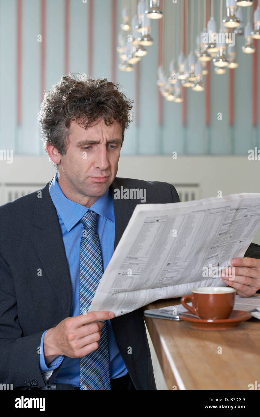Businessman at bar reading paper, doubt Stock Photo
