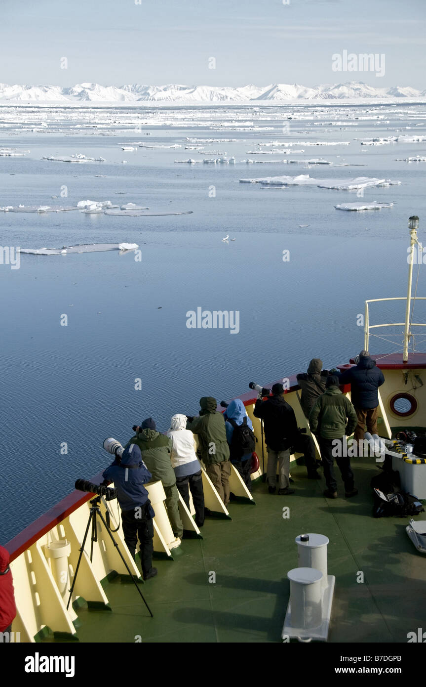 eco-tourists and photographers on the bow of the expedition vessle Polar Star watching for exciting events in the ice off north Stock Photo