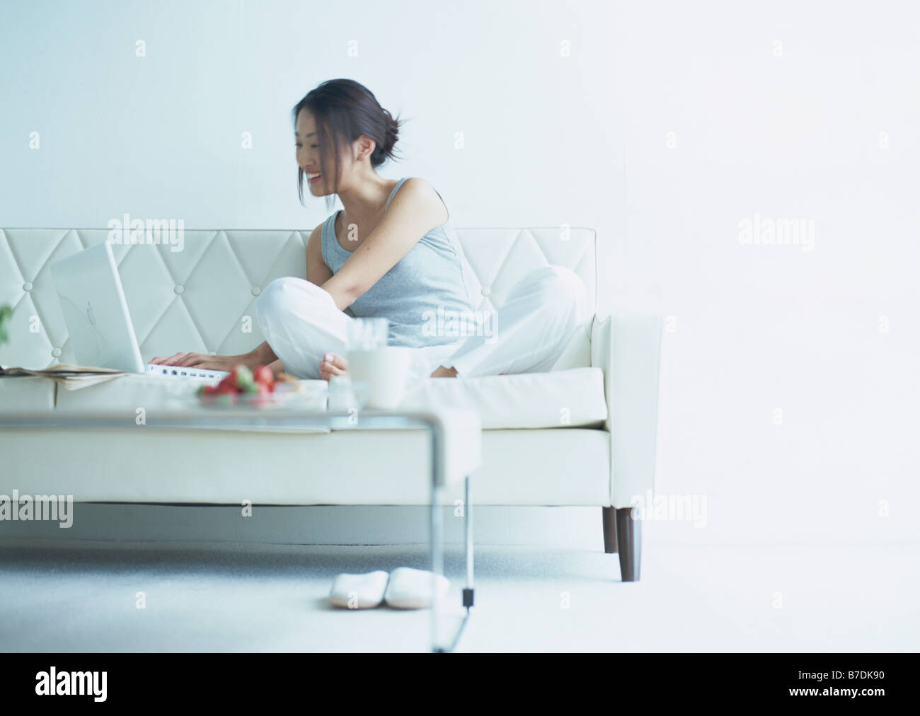 A smiling woman using laptop on sofa Stock Photo - Alamy