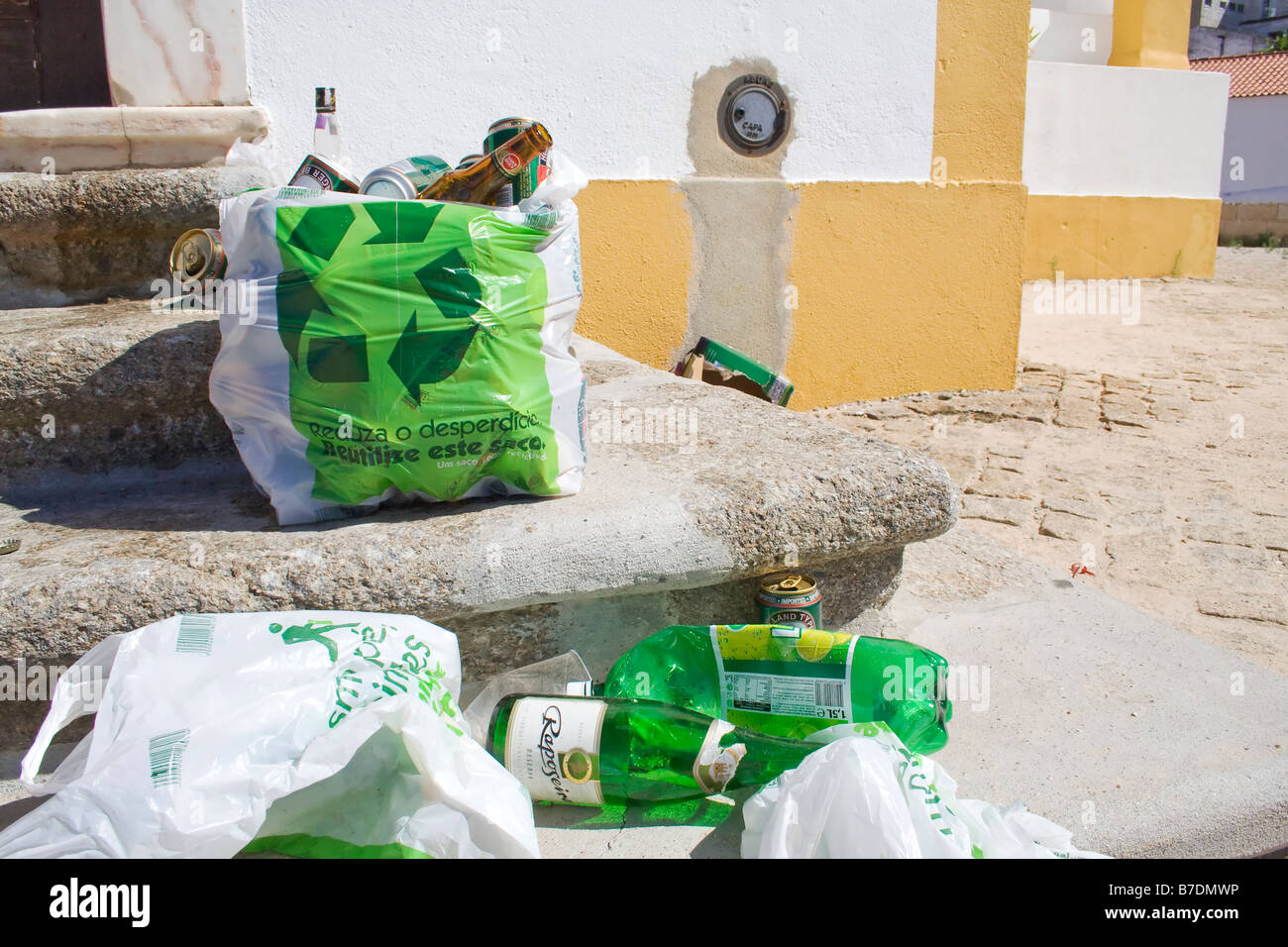 Ironic image, where plastic bags publicizing the recycling act end up filled with garbage, spread around in front of a monument. Stock Photo