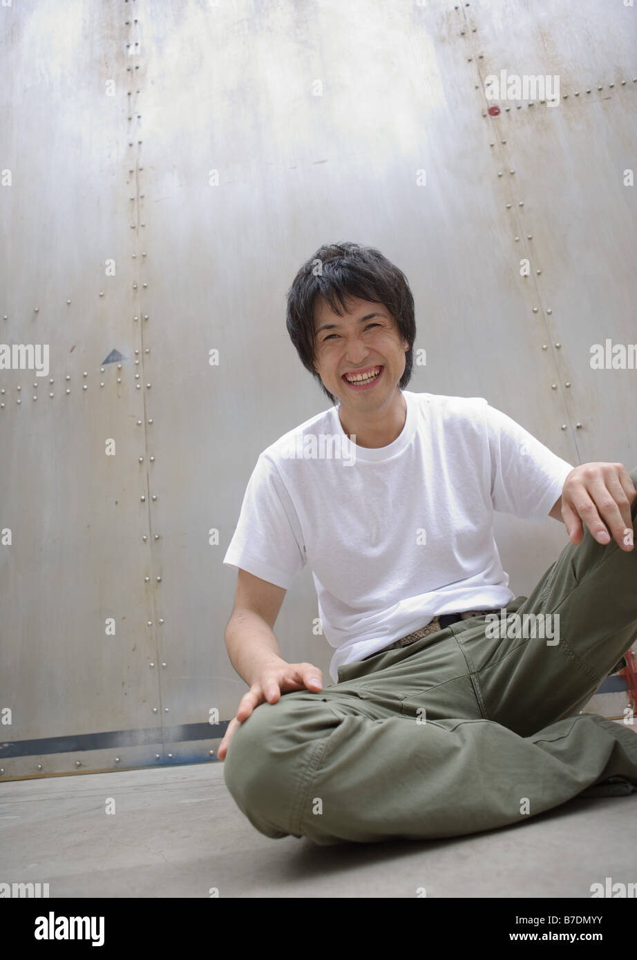 Smiling man sitting on floor Stock Photo - Alamy