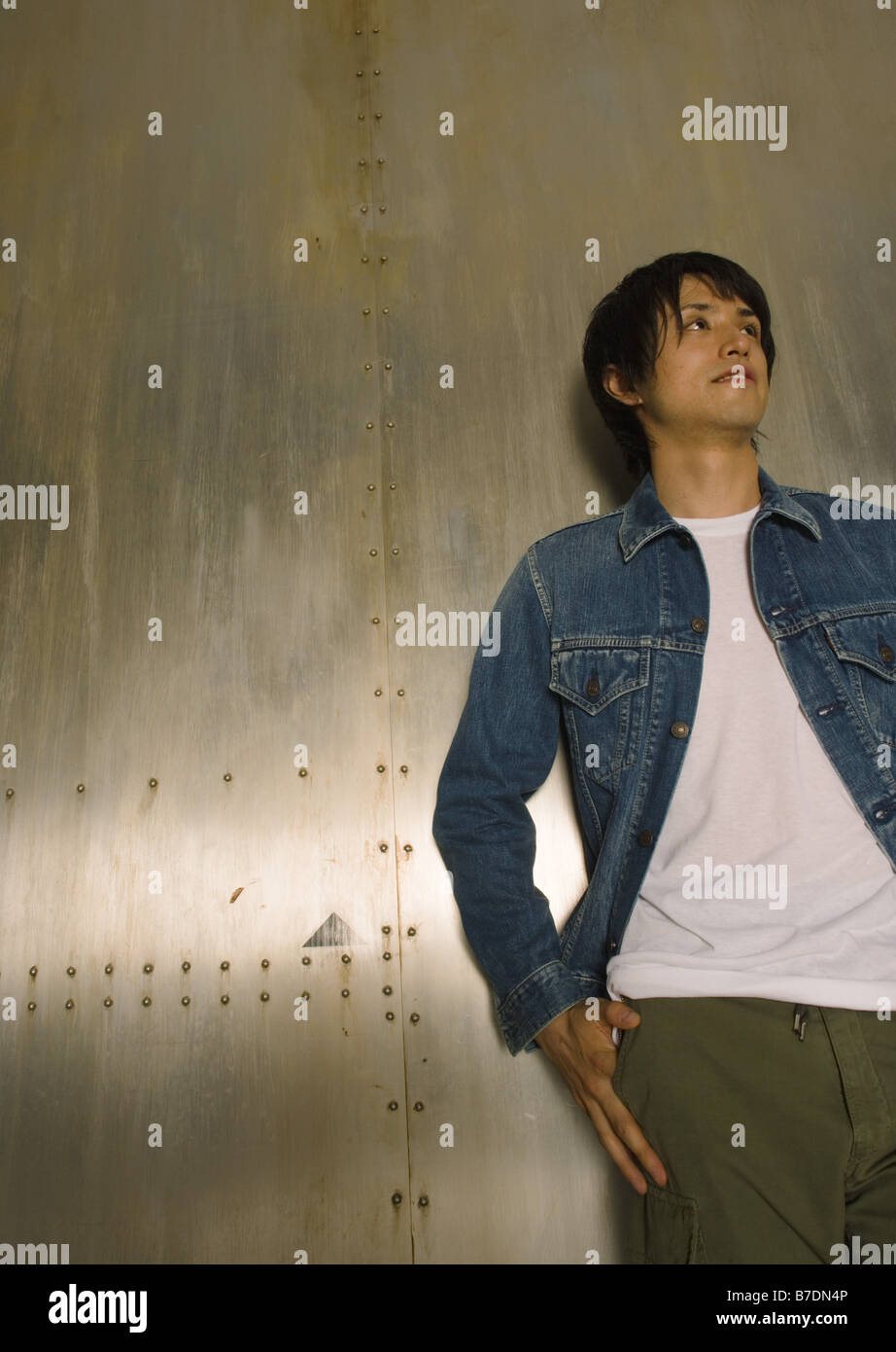 Young man standing by wall Stock Photo - Alamy