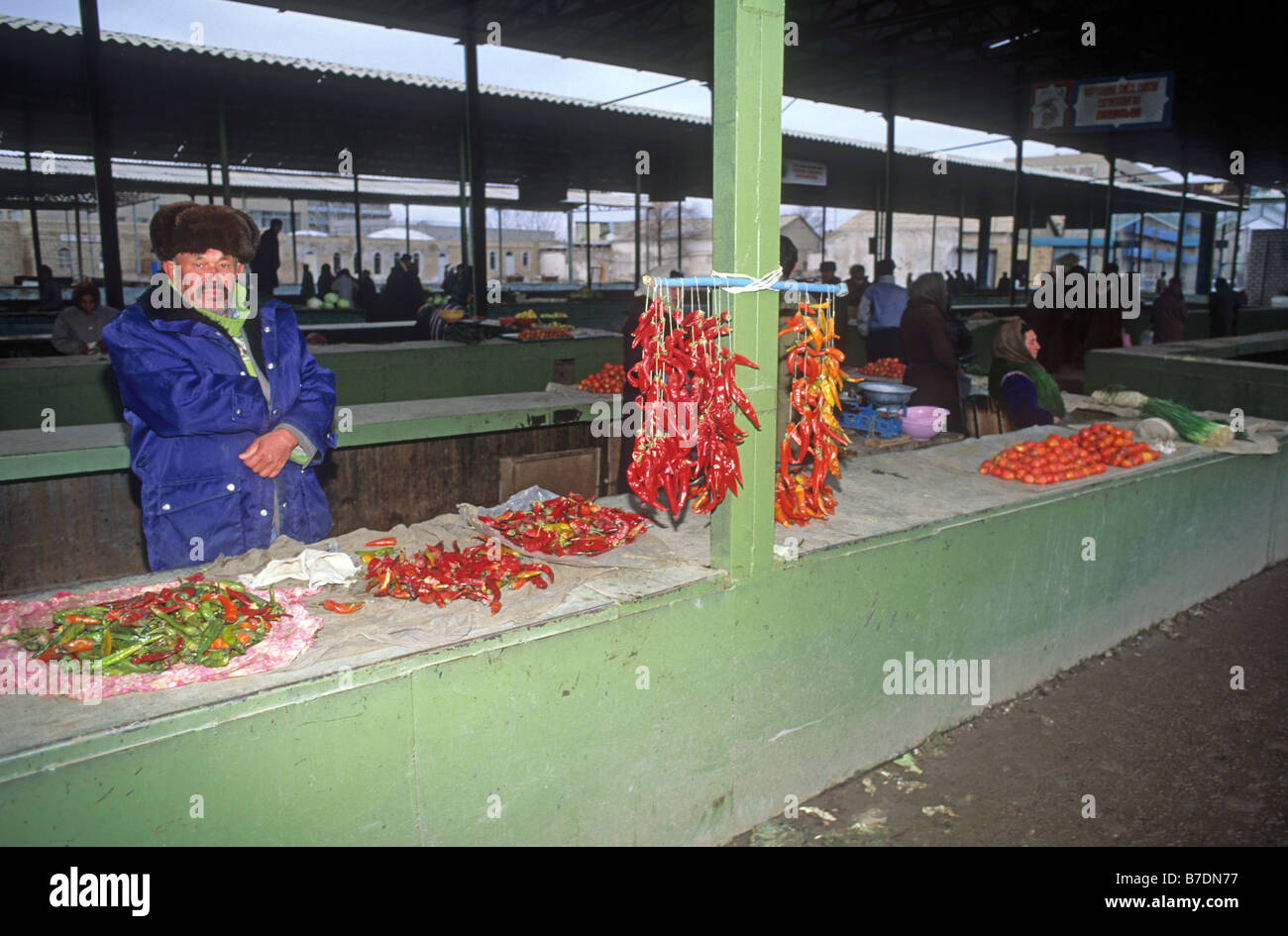 Man in fur hat selling chilli peppers and a few onions in Urgench bazaar near Khiva Uzbekistan Asia Stock Photo