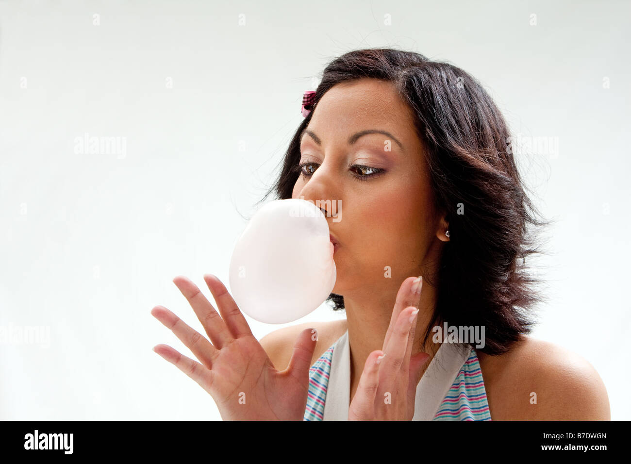 Beautiful Latina girl with crossed eyes blowing a bubblegum bubble isolated Stock Photo