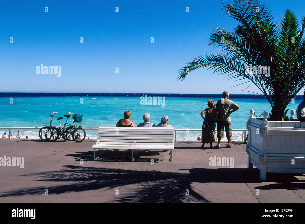 People seating in a bench faces the mediteranean sea in Nice Stock Photo