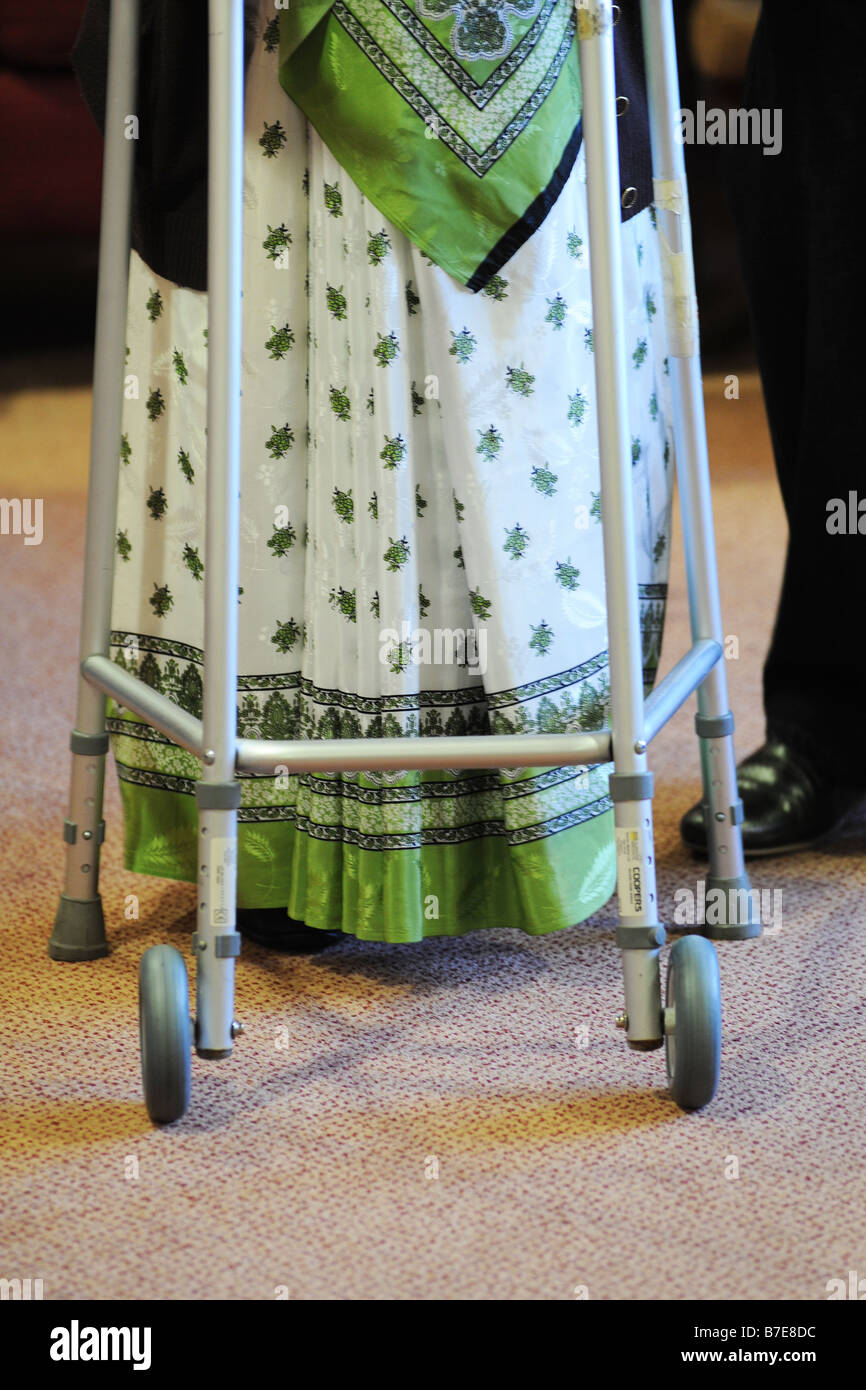 An elderly Sikh lady is helped to her chair in a multicultural extra Care home Bradford West Yorkshire Stock Photo