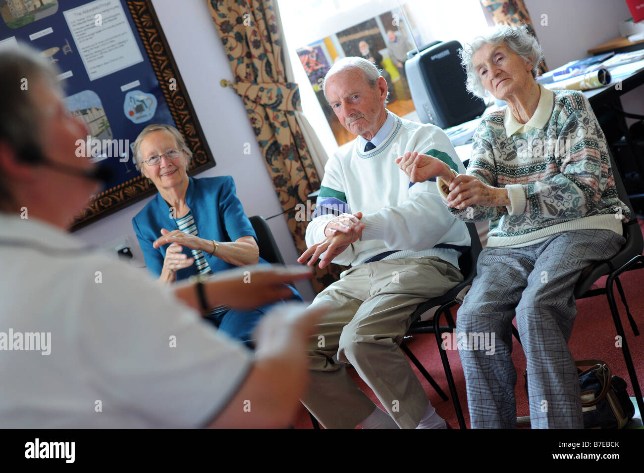 Elderly people participate in chair exercises during a health promotion day run by the Bradford Council Ilkley West Yorkshire Stock Photo