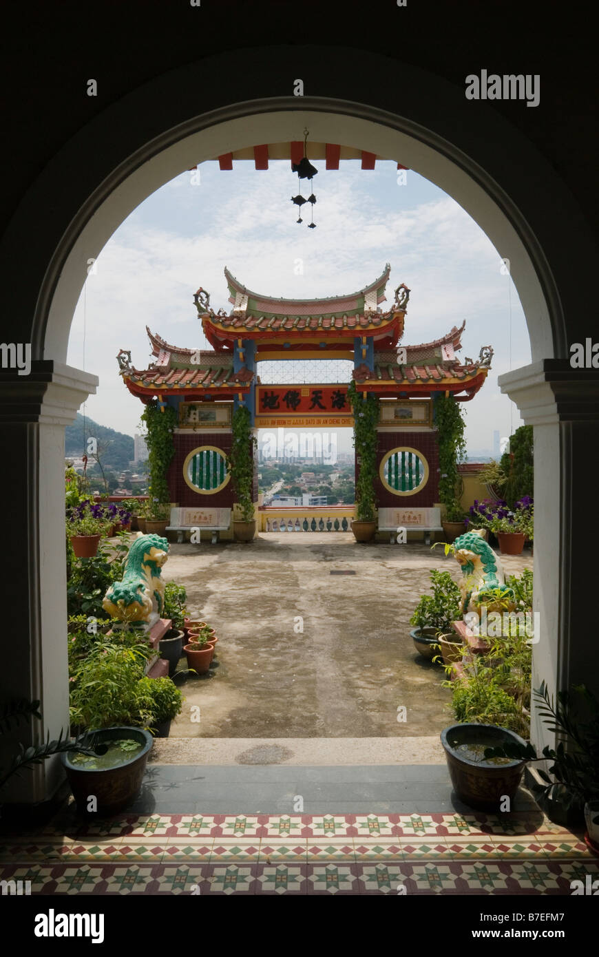 An arched doorway frames a traditional ornate gateway with views over Georgetown at the Buddhist Kek Lok Si Temple, Air Itam, Penang, Malaysia Stock Photo