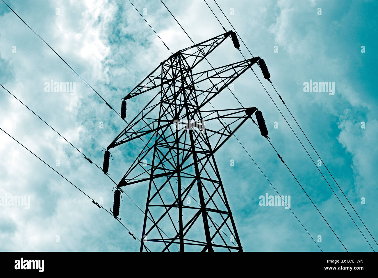 ELECTRICAL POWER PYLON WITH SUPPLY CABLES OR LINES AGAINST A CLOUDY SKY ELECTRIC Stock Photo