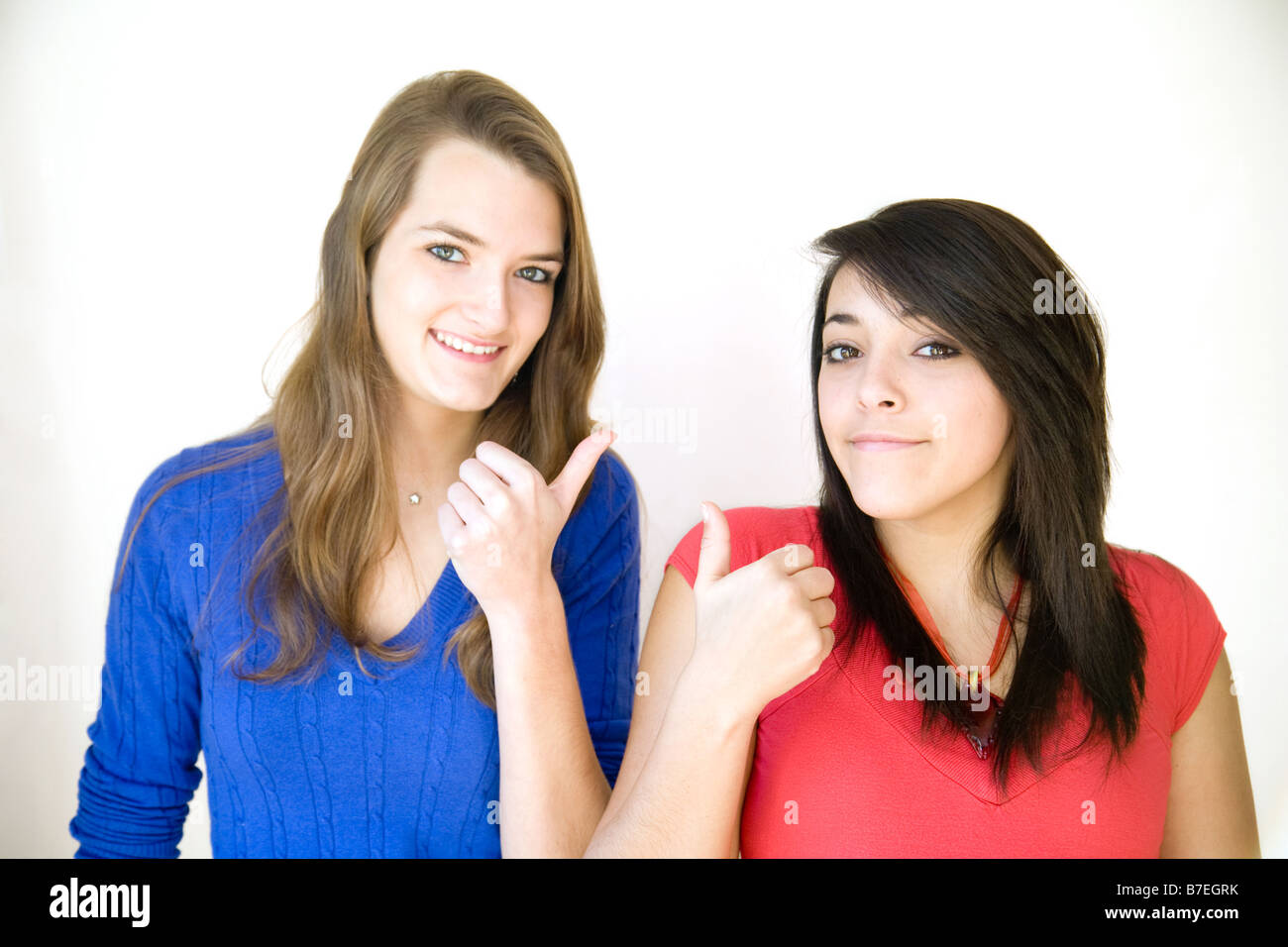 Two teenage girls standing side by side giving the thumbs up sign Stock Photo