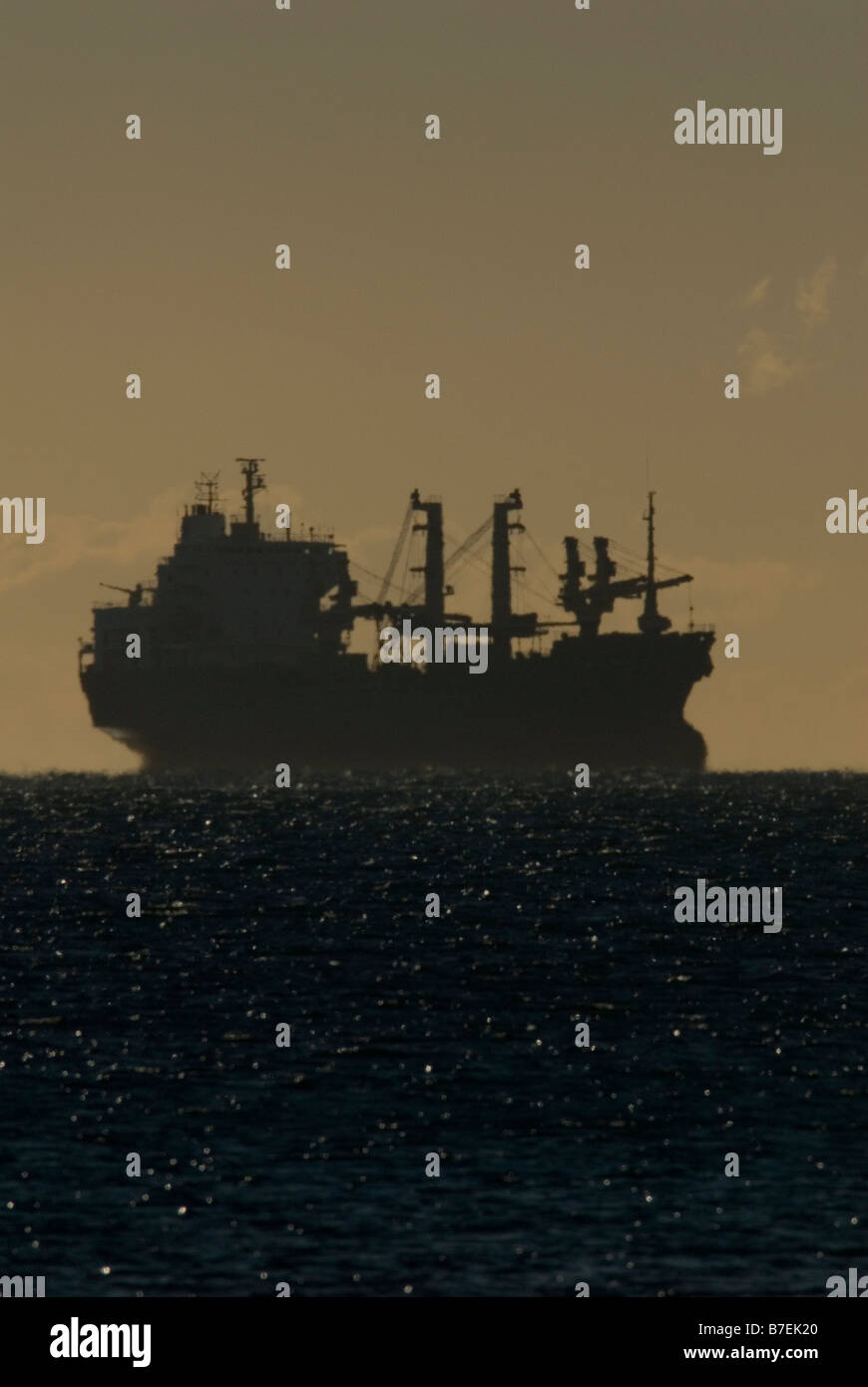 Silhouette of cargo ship at sea Stock Photo