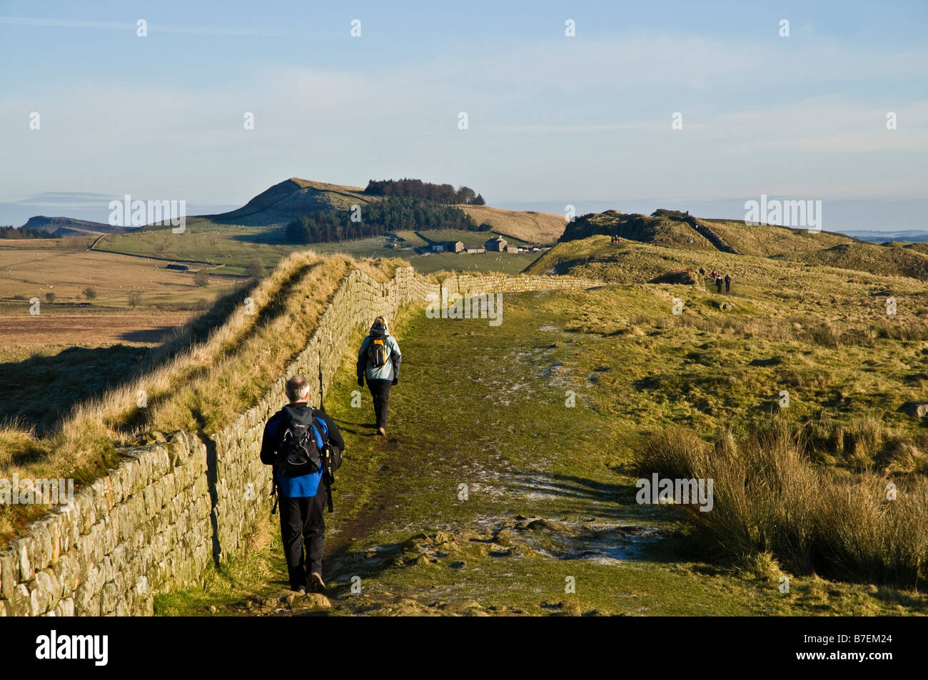 dh Steel Rigg HADRIANS WALL NORTHUMBRIA Walkers Roman wall Northumberland National Park hikers couple winter walking public footpath uk Stock Photo