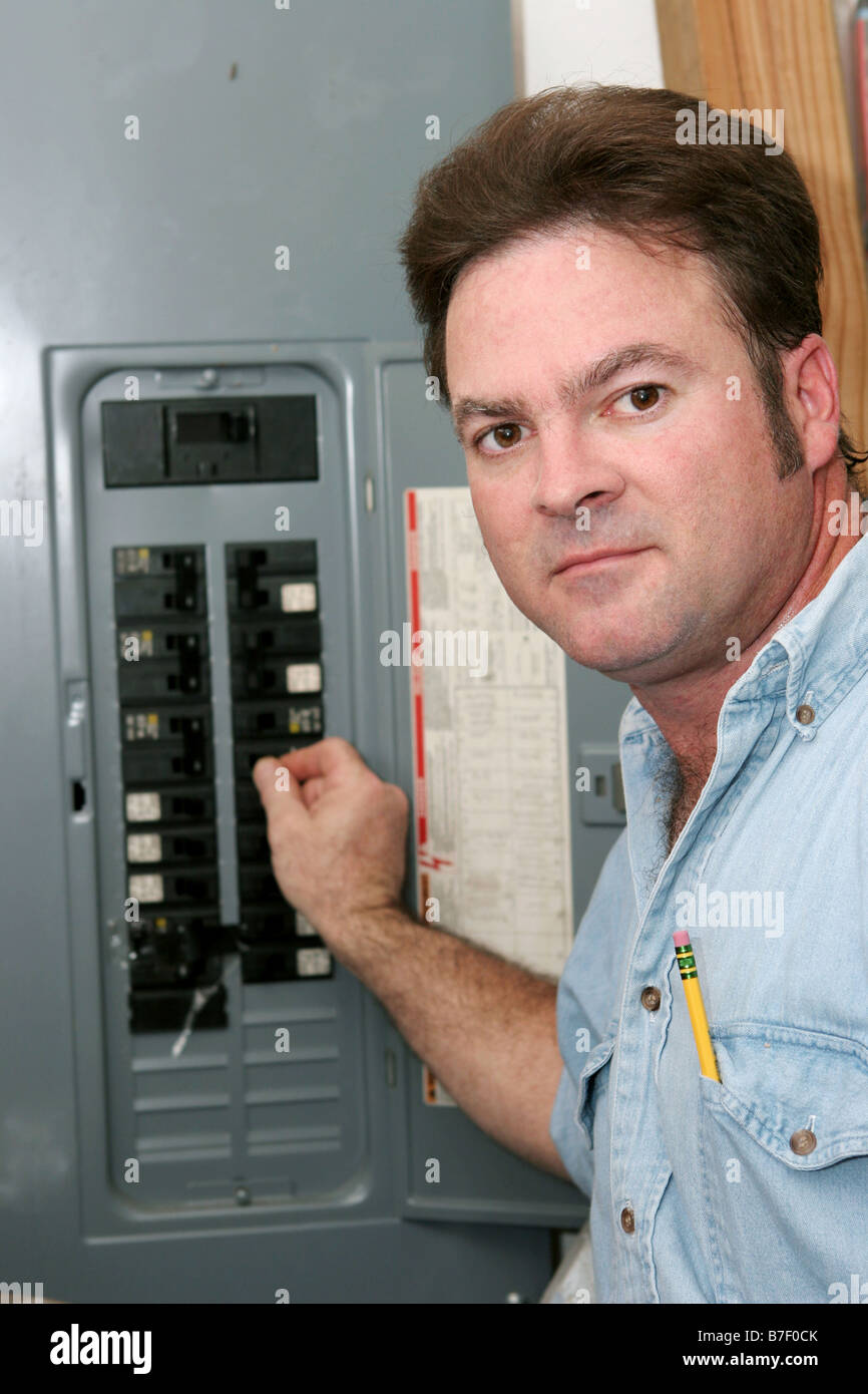 An electrician at an electrical panel turning off the breaker before