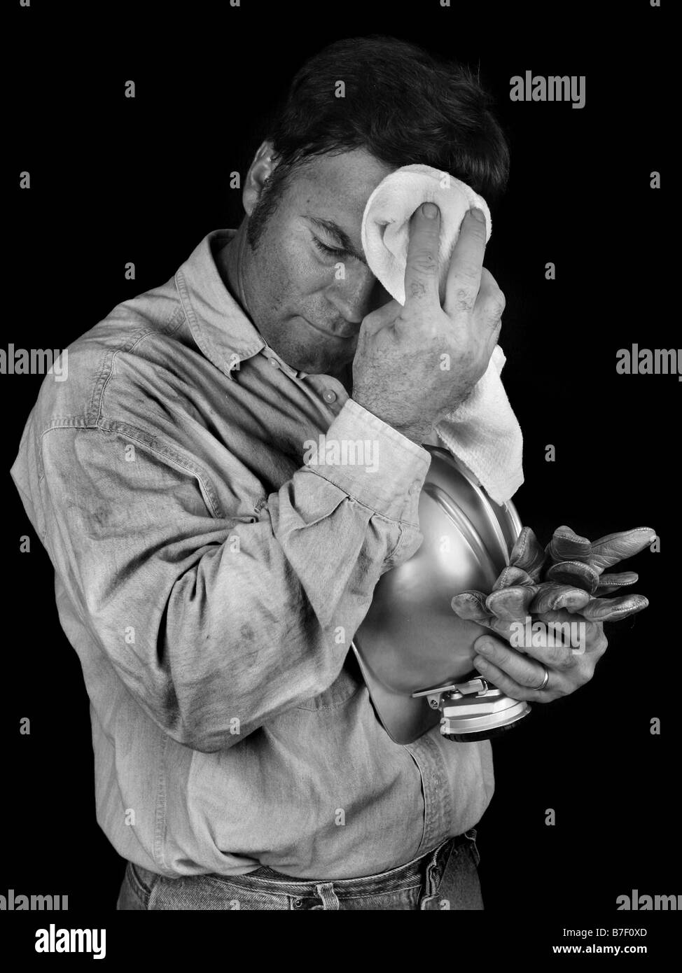 A tired coal miner wiping coal dust from his brow after a long day of work Black White Stock Photo