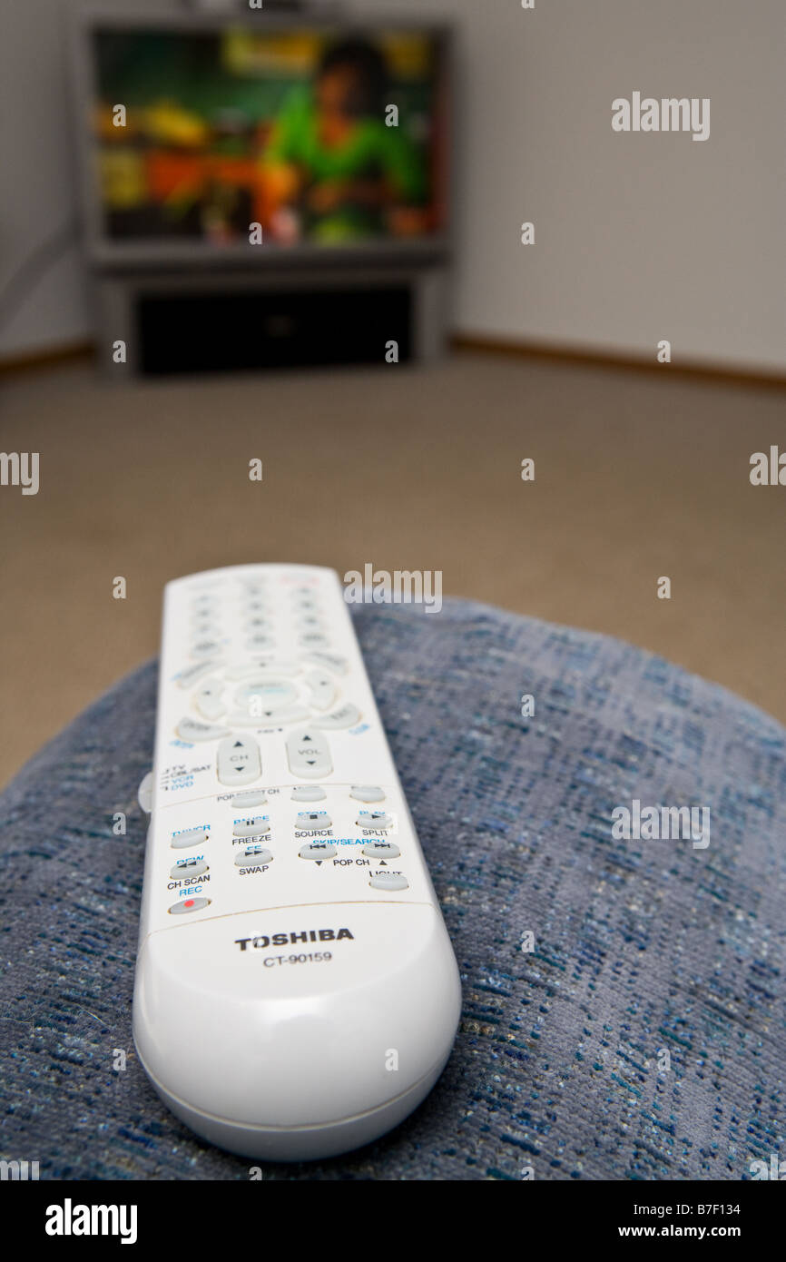 A remote control sitting on the arm of an easy chair Stock Photo
