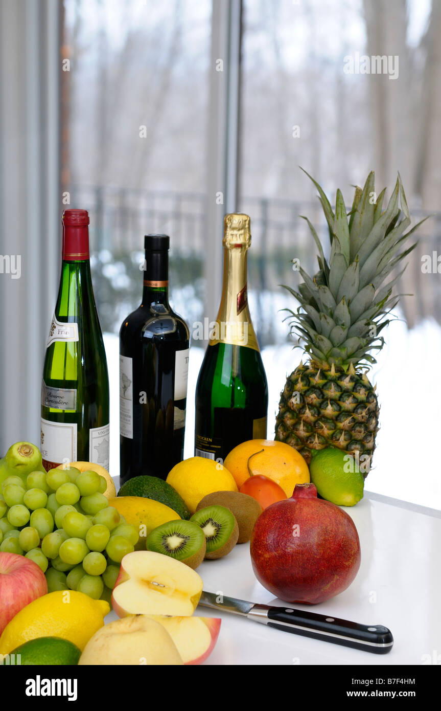Cutting board in kitchen surrounded by fresh fruit and wine bottles on a winter day Stock Photo