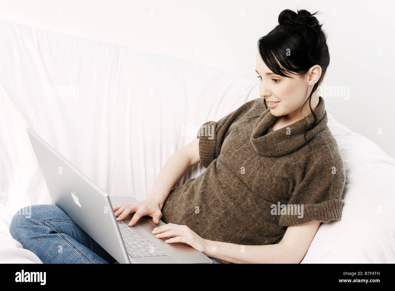 Young woman sitting on a sofa using a laptop computer Stock Photo - Alamy