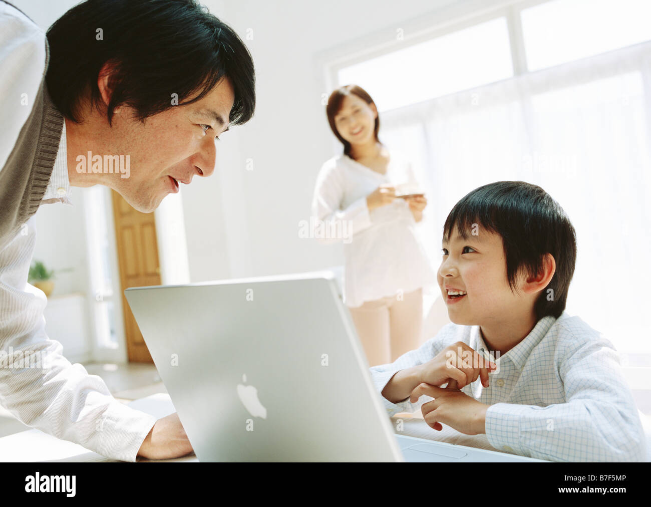 Boy using laptop at table with father Stock Photo - Alamy