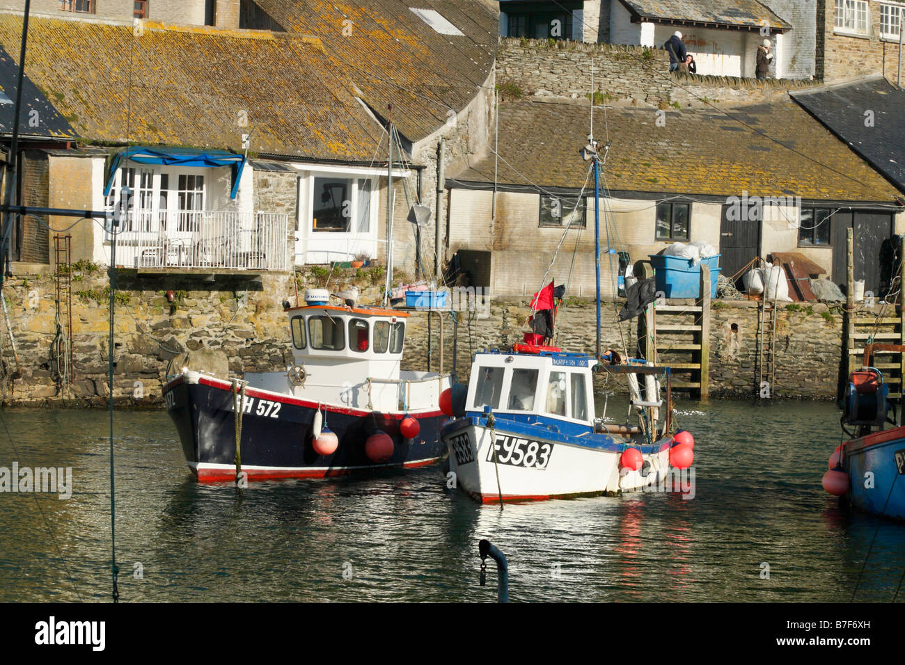 The sun catches  the fishing boats sheltering in Polperro harbour on a winter day in January Stock Photo