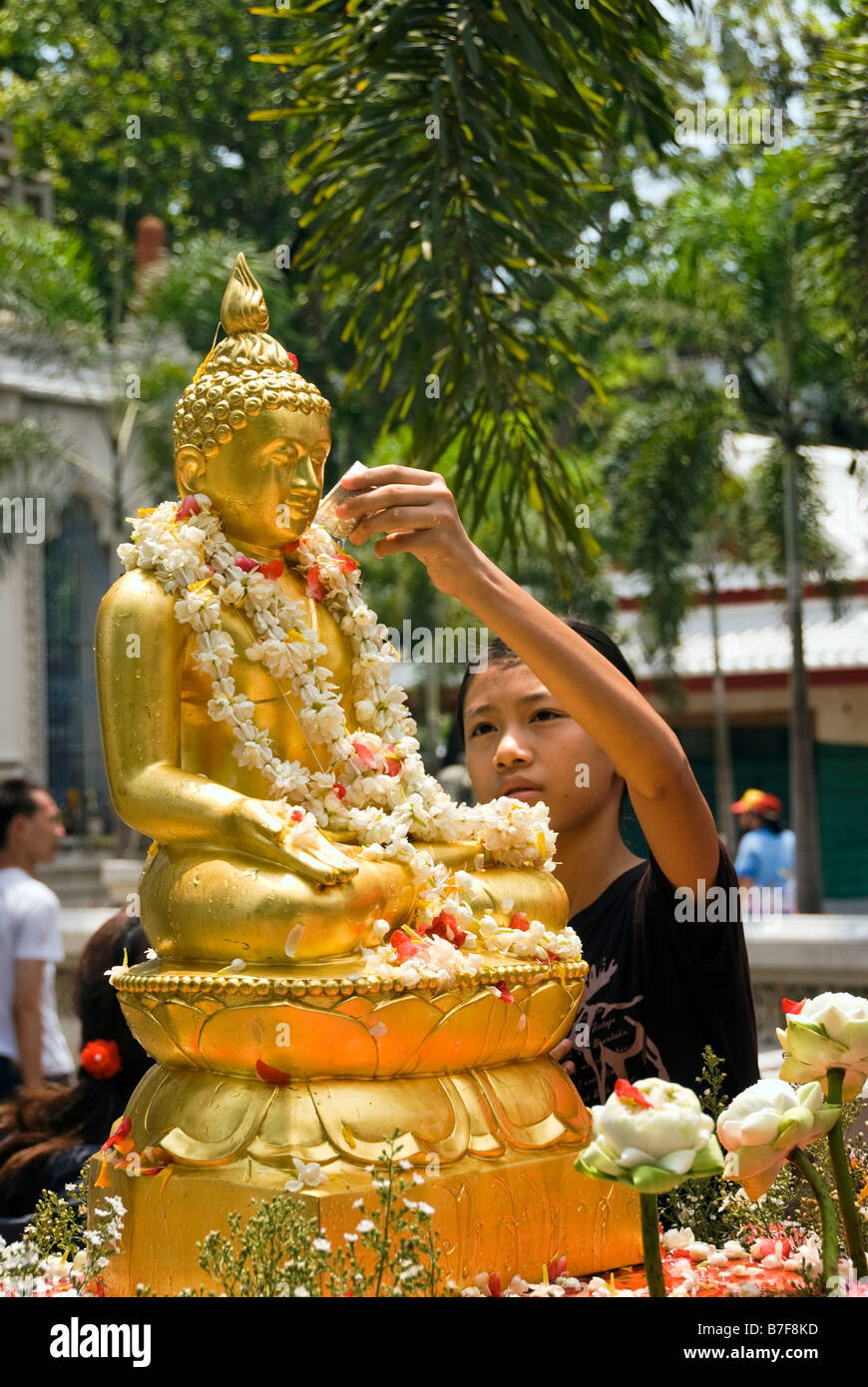 Young boy pours water over statue of Buddha during Thai new year celebrations of Songkran - Wat Bowan Niwet Bangkok Thailand Stock Photo