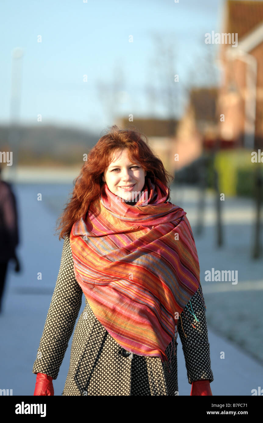 Young woman with red hair; dressed in coat, gloves and scarf on a bright but cold day. Stock Photo
