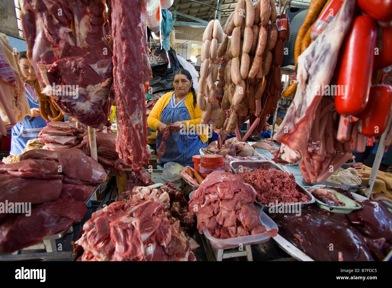 Indoors Market trader selling meat and poultry, saussages hanging in Ecuador Horizontal 72053 Ecuador Cuenca Stock Photo