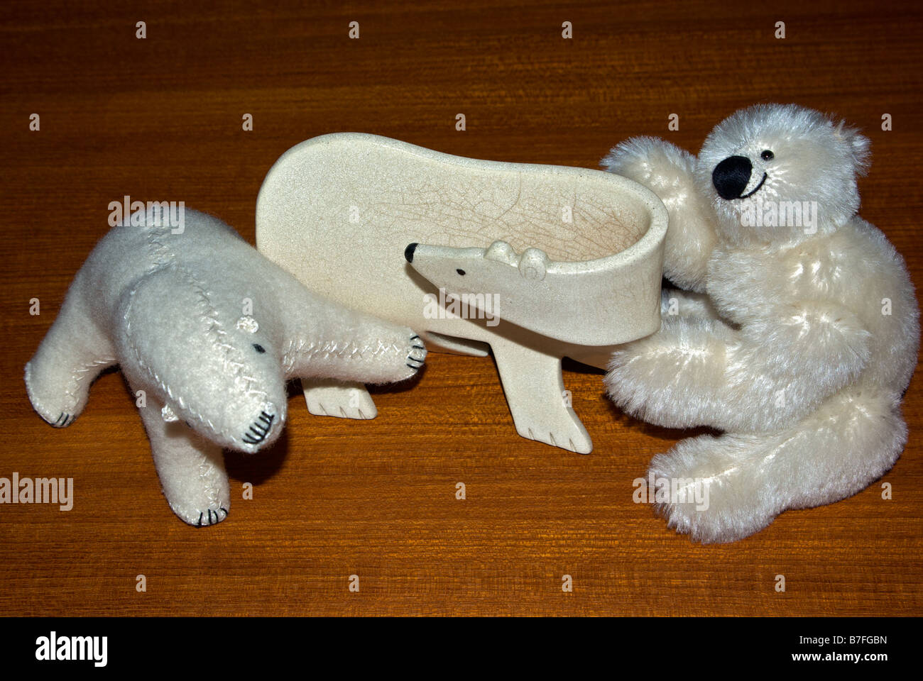 Ceramic and stuffed toy polar bears on teakwood table Stock Photo