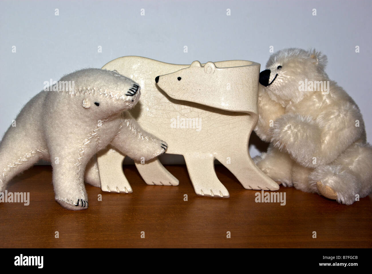 Ceramic and stuffed toy polar bears on teakwood table Stock Photo
