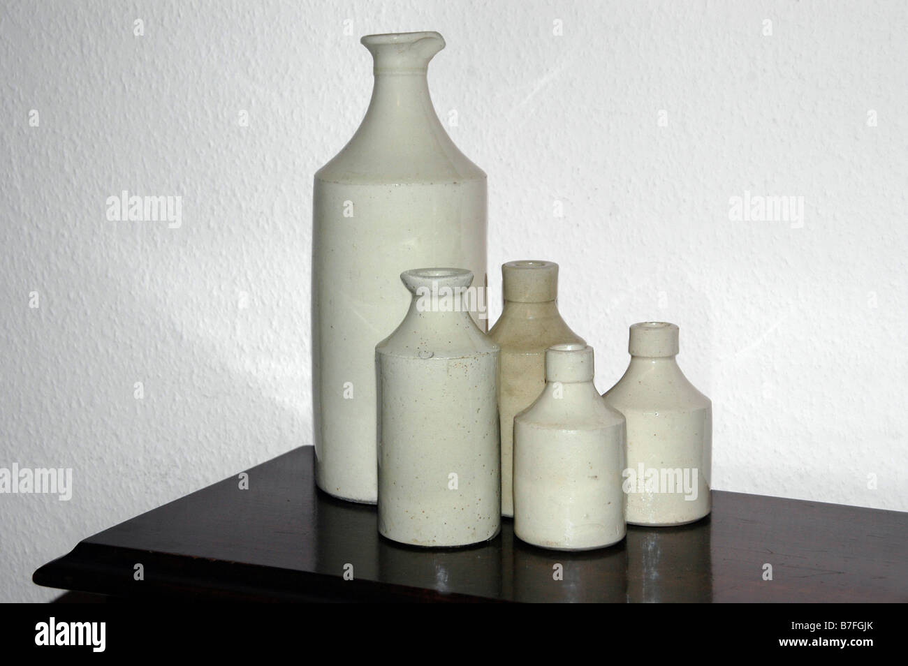 Old fashioned earthenware bottles, sit on a wooden table. Stock Photo