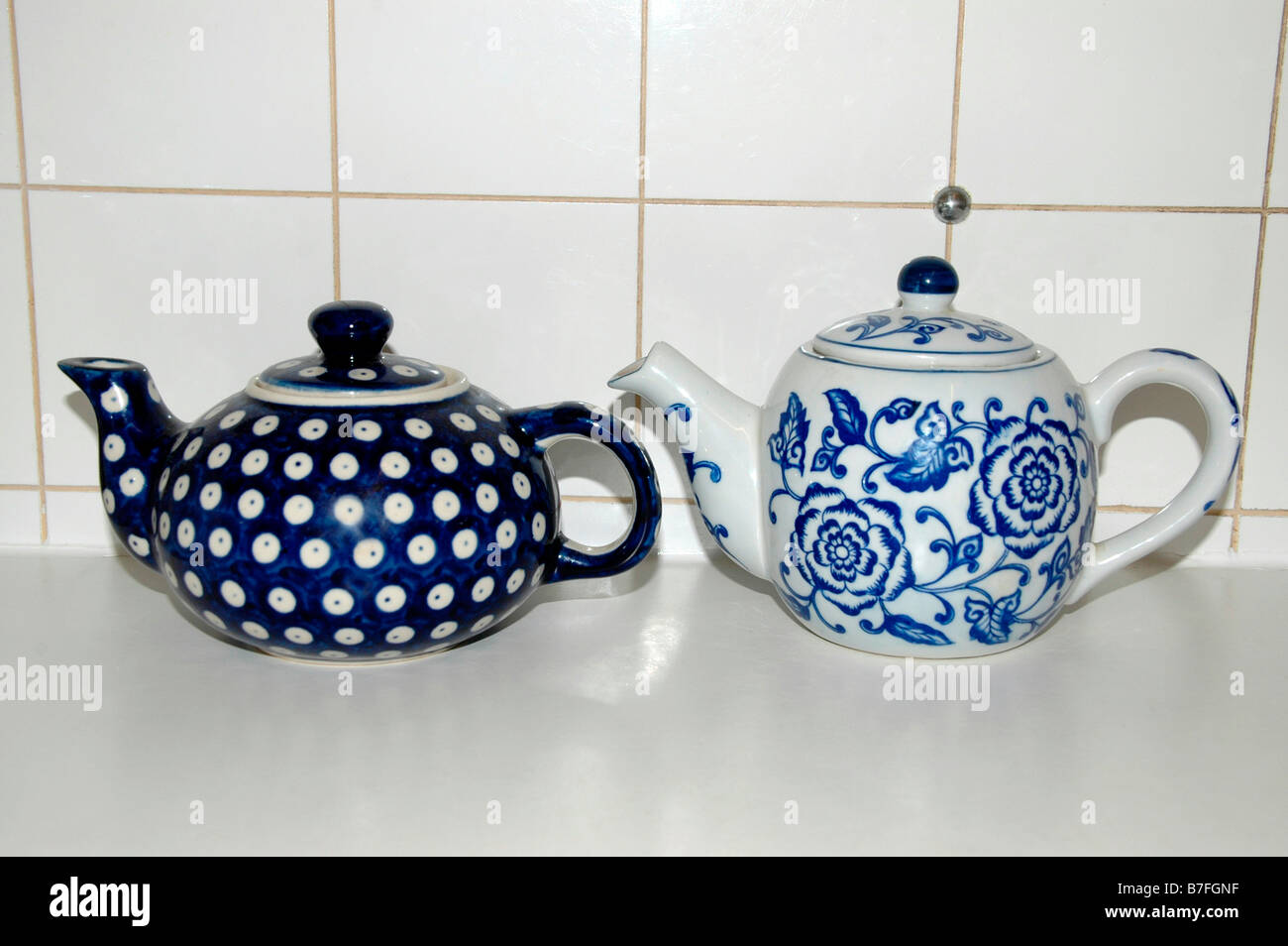 Two porcelain teapots sit on a kitchen ledge. Stock Photo