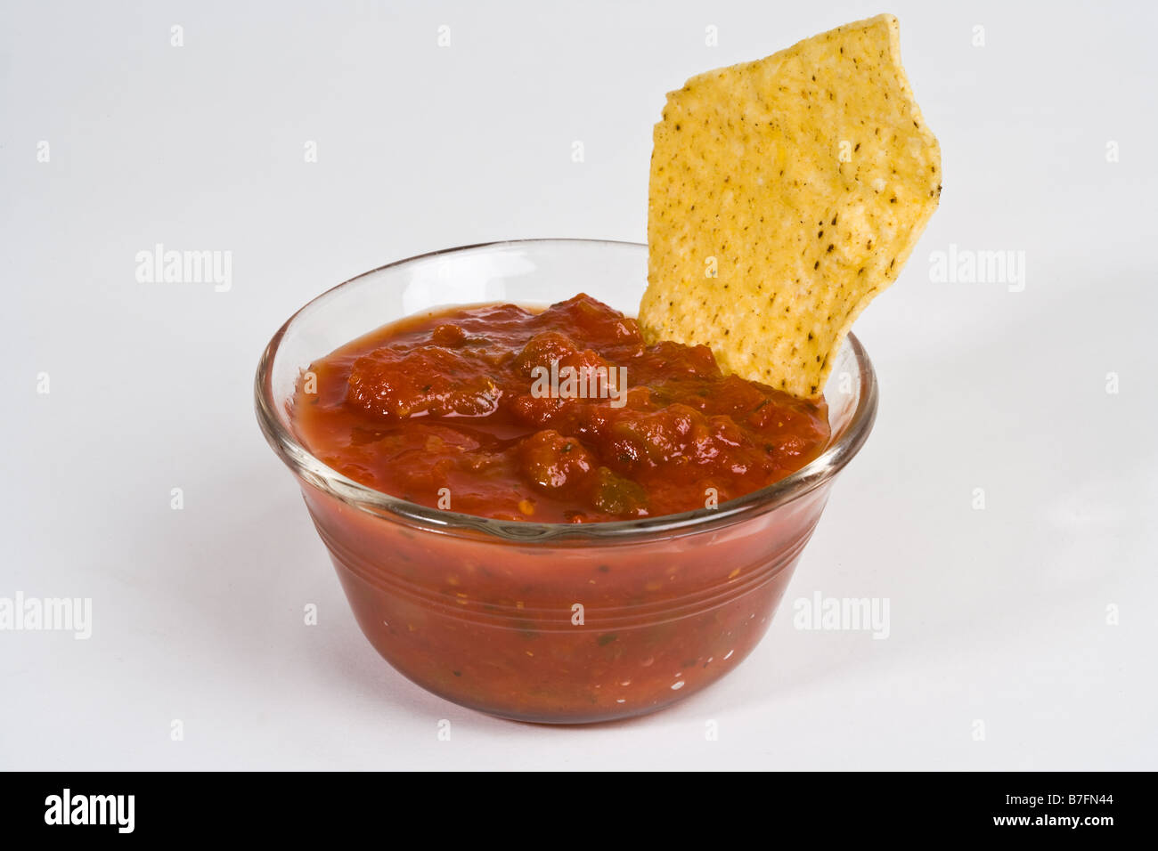 A corn chip dipped in a bowl of salsa Stock Photo