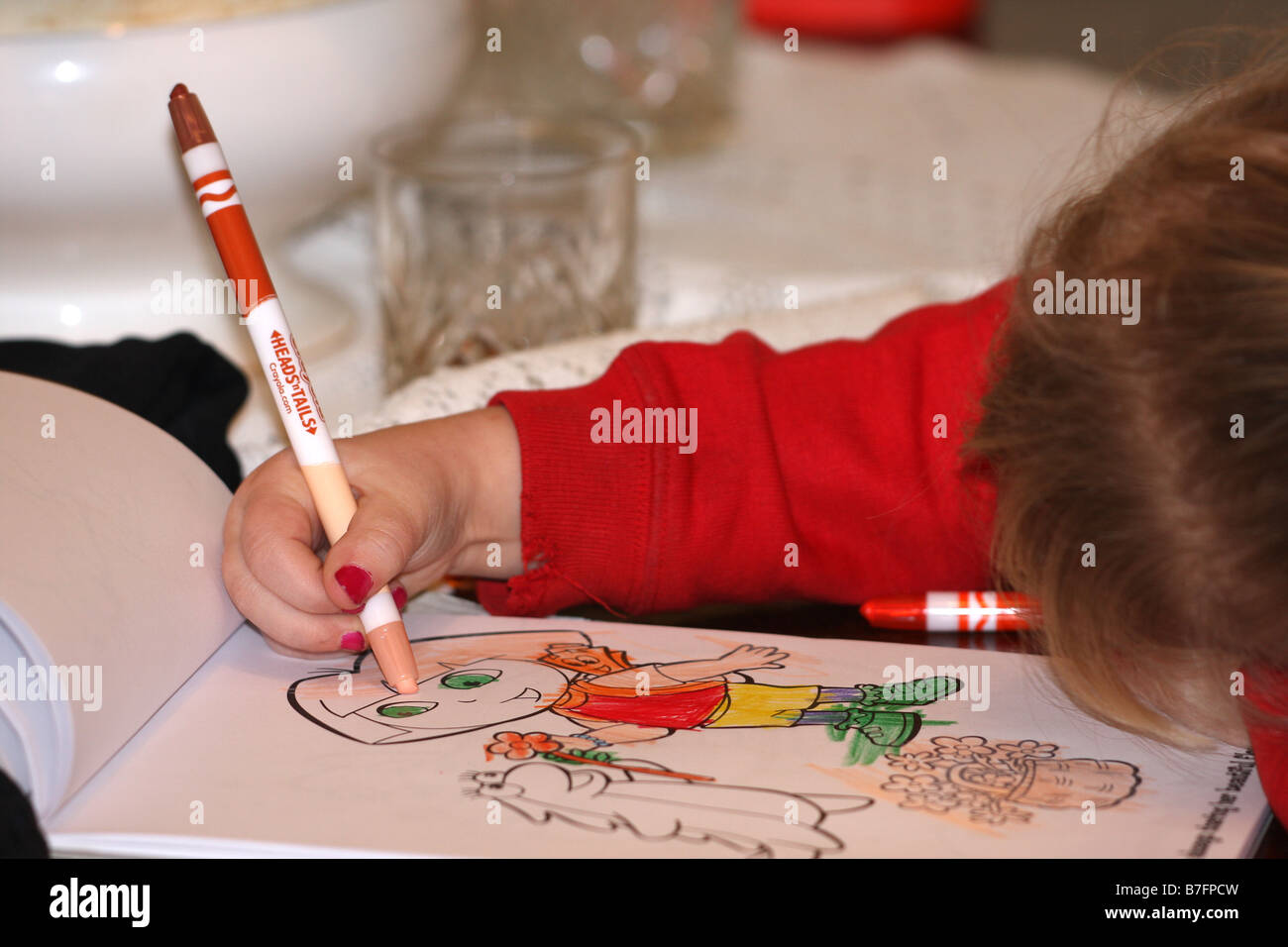 Child using paint pen to colour in image in colouring book Stock Photo