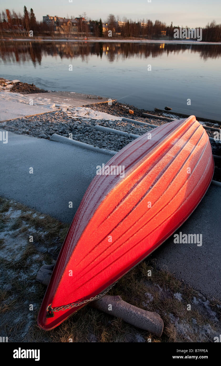 Red fiberglass rowboat / skiff / dinghy , upturned for Winter storage , is covered with frost , Finland Stock Photo