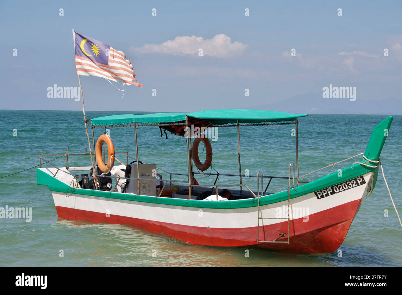 Small wooden boat used around the coast of Penang, Malaysia, flying the Malaysian flag. Stock Photo