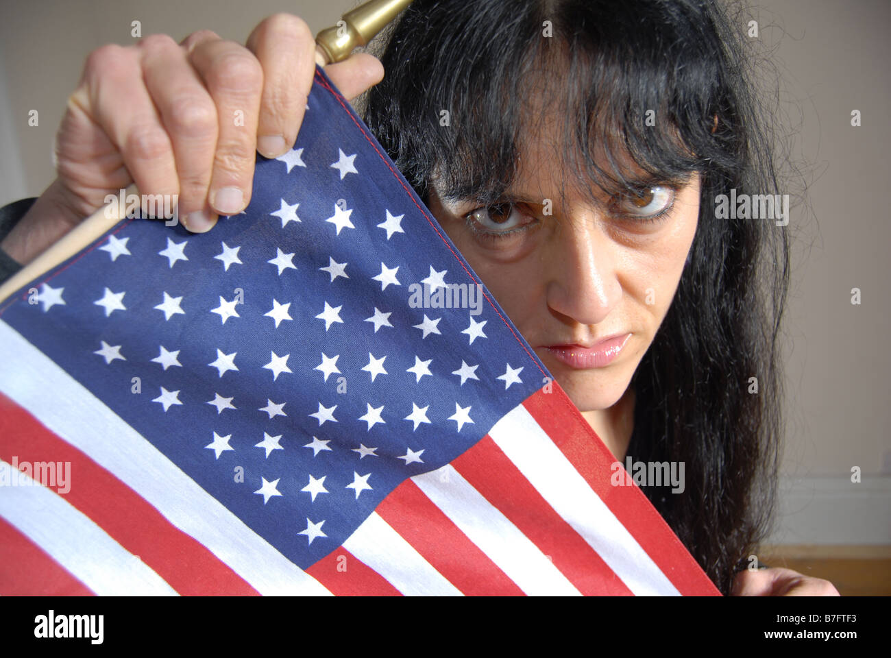 A no nonsence woman with black hair holding the American Stars & Stripes Stock Photo