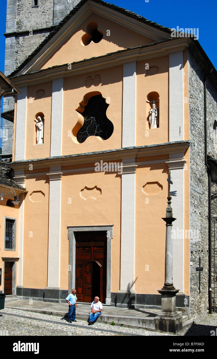 Two men chatting in front of the San Gottardo parish church, Intragna, Centovalli, Ticino, Switzerland Stock Photo