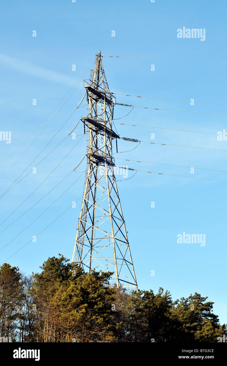 High tension electric tower for transmitting electricity on a hill surrounded by trees Stock Photo