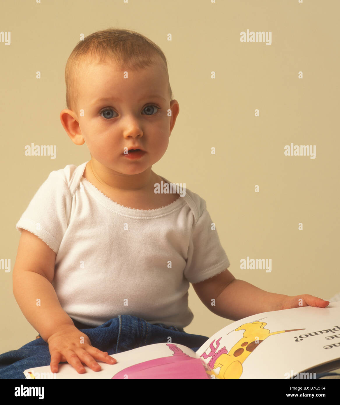 baby sitting up and looking at a Spot pop up book Stock Photo