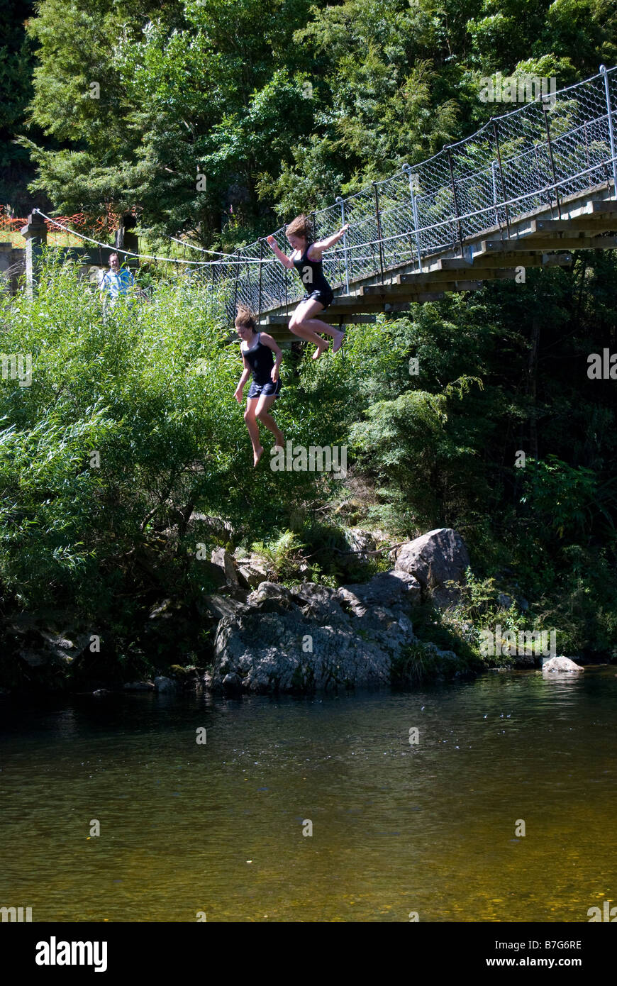 Girls jumping off swing bridge over Inangahua River, Reefton, Buller District, West Coast, New Zealand Stock Photo