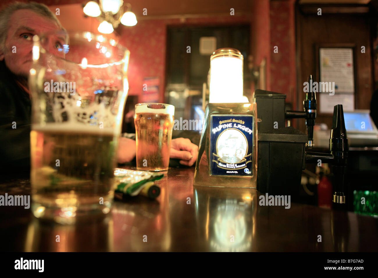 In a London pub, a man at the bar, behind a pint of lager Stock Photo