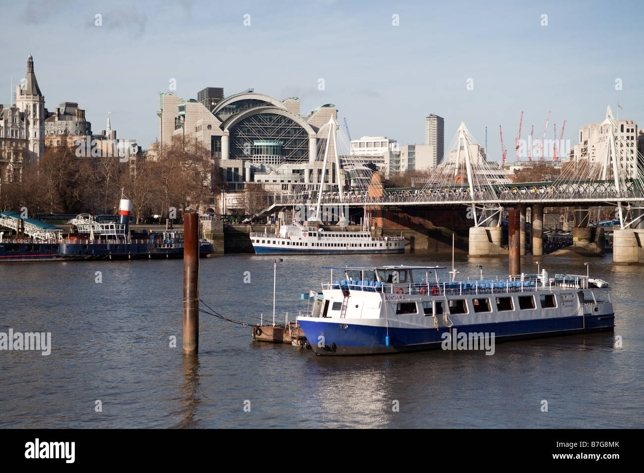 Tourist boat on the Thames in London with Charing Cross Station and the Hungerford Bridge behind Stock Photo