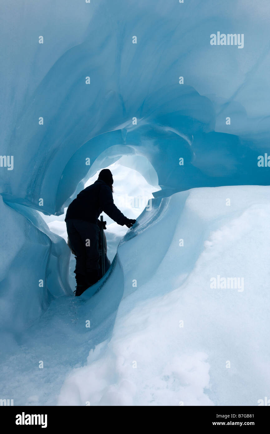 Hiker through blue ice cave. Heli hike trip. Fox Glacier. South Island. New Zealand. Stock Photo