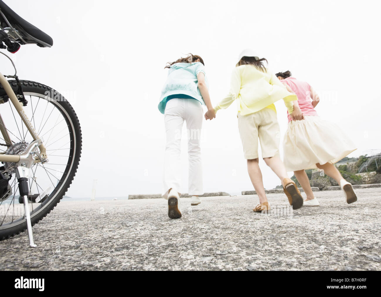 Three women running with holding hands Stock Photo - Alamy