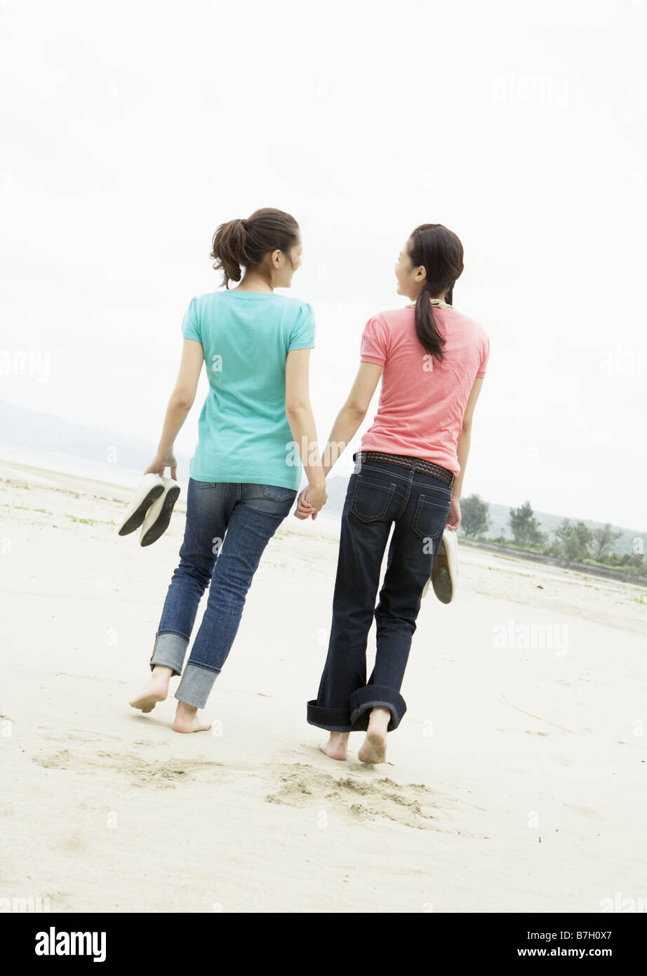 Two women walking on a beach Stock Photo - Alamy