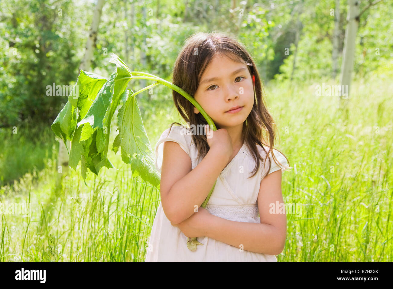 Young Asian girl holding plant stem in field Stock Photo