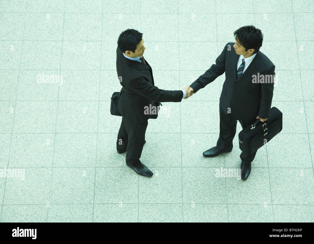 Businessmen shaking hands in office lobby Stock Photo