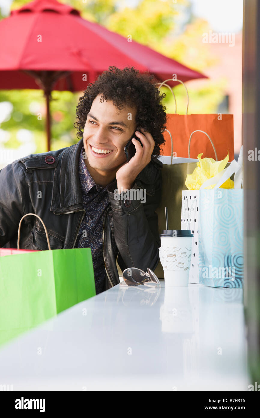 Middle Eastern man with shopping bags talking on cell phone Stock Photo