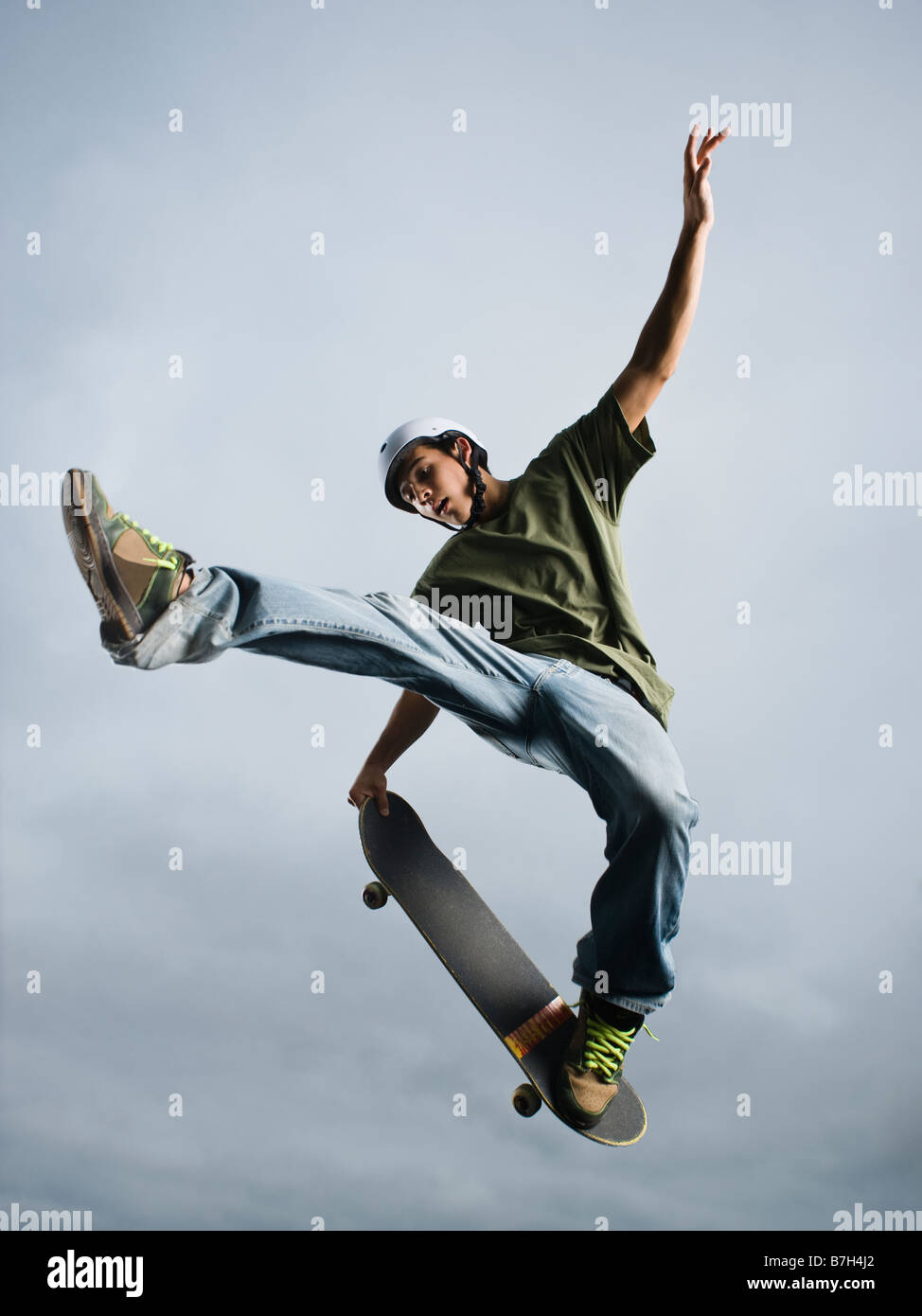 Mixed race teenager in mid-air on skateboard Stock Photo