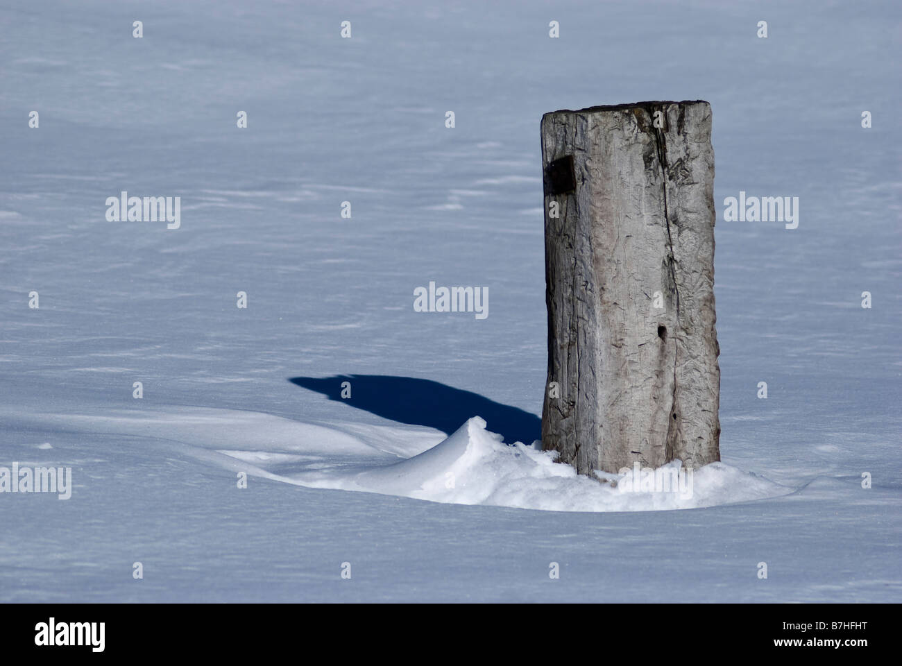 A fence post protrudes through the snow Stock Photo